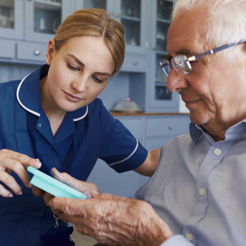 Nurse Helping Senior Man To Organize Medication On Home Visit